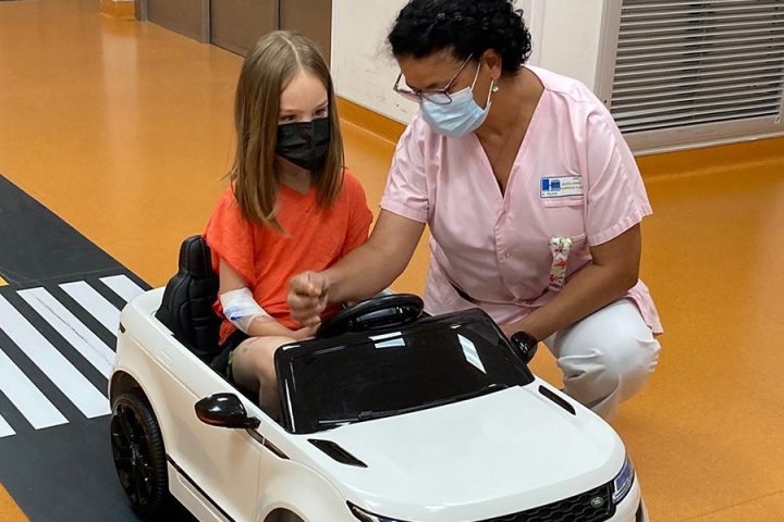 Jeune patiente se rendant au bloc opératoire pédiatrique avec une voiturette électrique sur un circuit